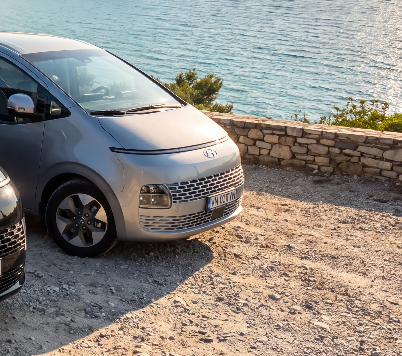 Hyundai Staria gri cu numărul VN 02 TYN, la apus deasupra unui golf